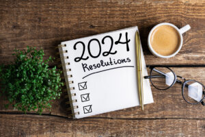 New year resolutions 2024 on desk. 2024 resolutions list with notebook, coffee cup on table. Goals, resolutions, plan, action, checklist concept.